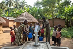Villagers gathered around a hand pump in a village